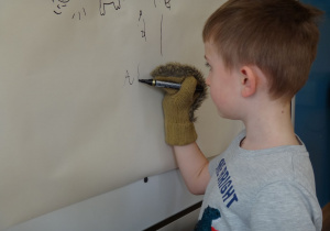 Dziecko pisze swoje imię w rękawiczce